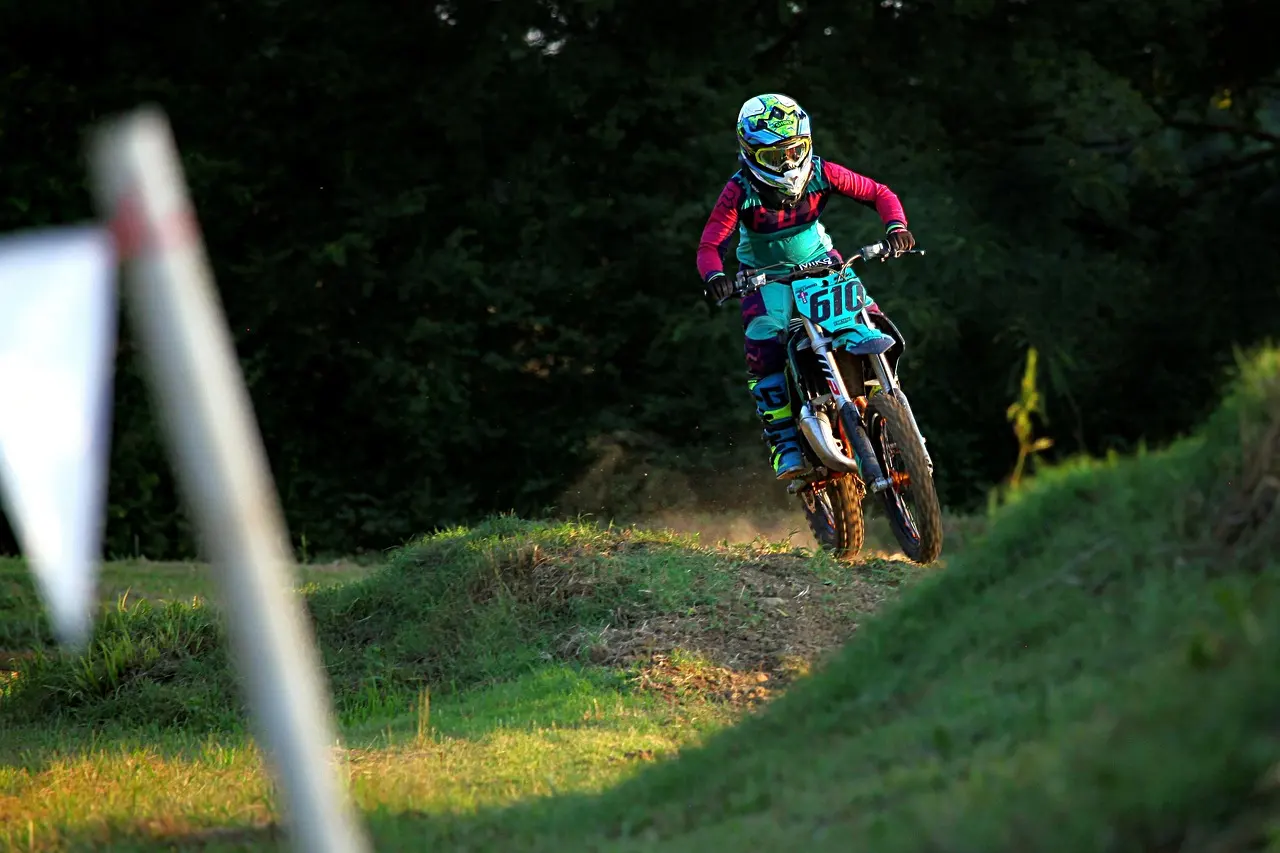 Dirt bike rider approaching a wooded motocross track section